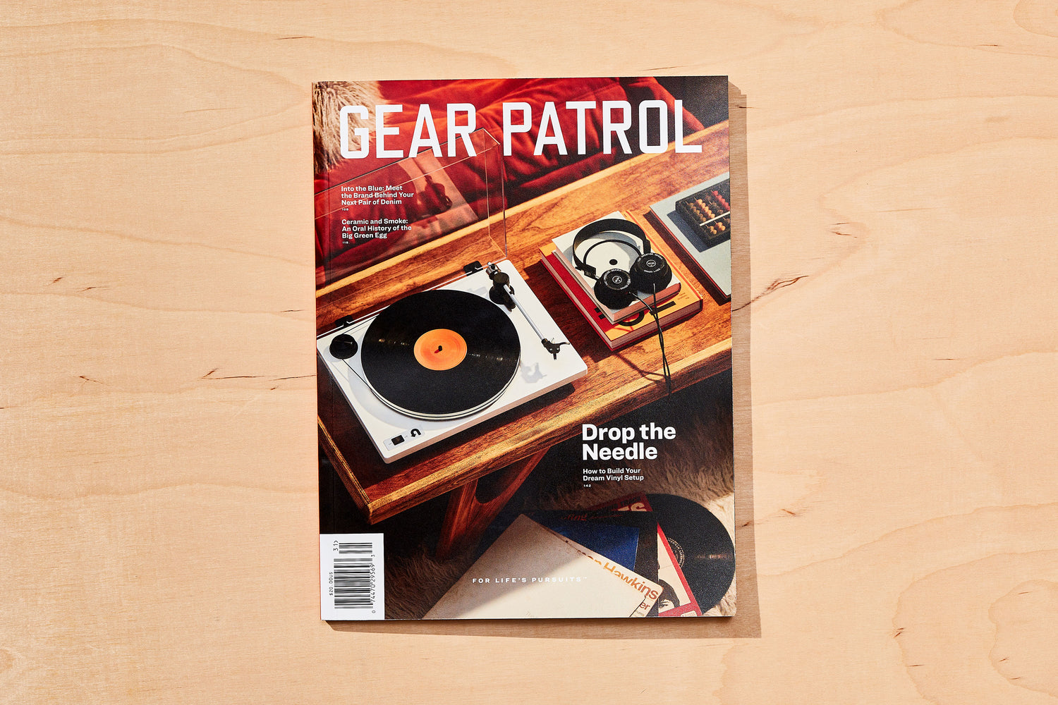 copies of gear patrol magazine, including issue twenty with record player and headphones on a wood coffee table