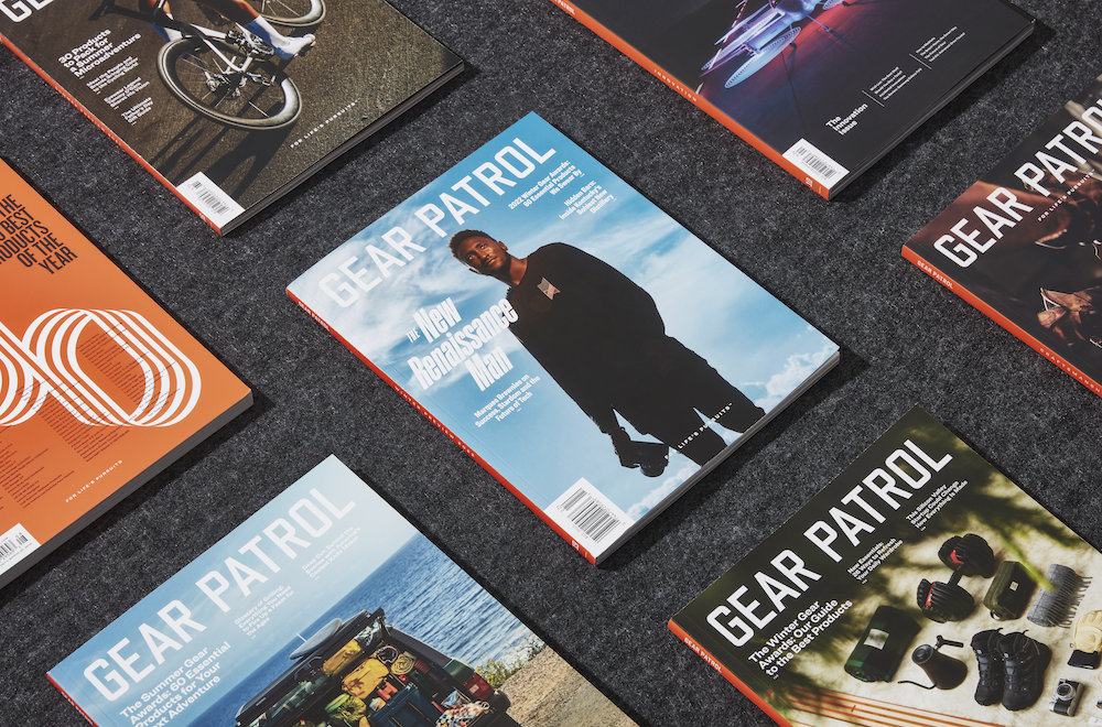 copies of gear patrol magazine, including issue nineteen with marques brownlee on the cover holding a camera in his hand as he stands in front of a blue sky