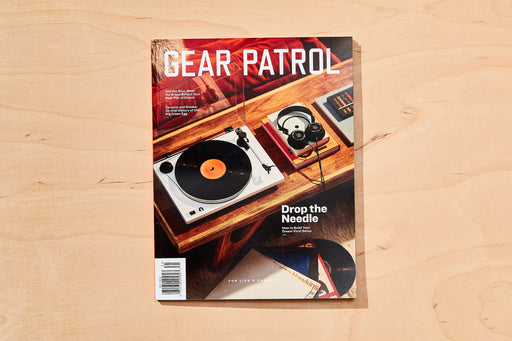 copies of gear patrol magazine, including issue twenty with record player and headphones on a wood coffee table