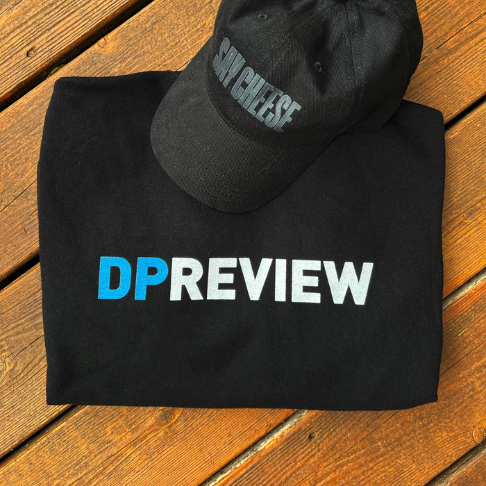 dpreview say cheese hat and dpreview crewneck sweatshirt folded on a wooden table