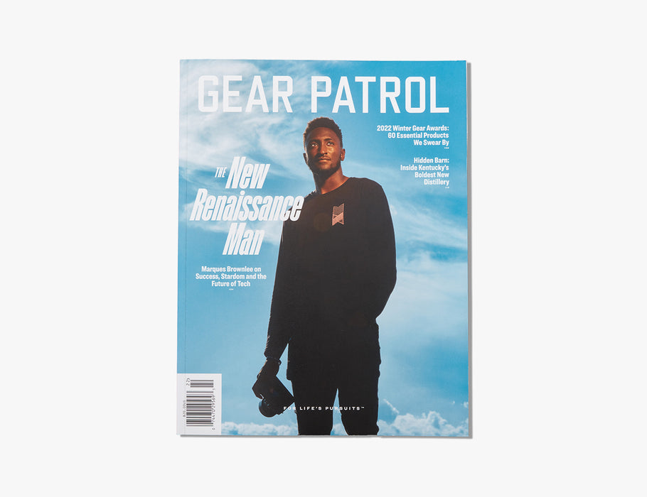 copies of gear patrol magazine, including issue nineteen with marques brownlee on the cover holding a camera in his hand as he stands in front of a blue sky 